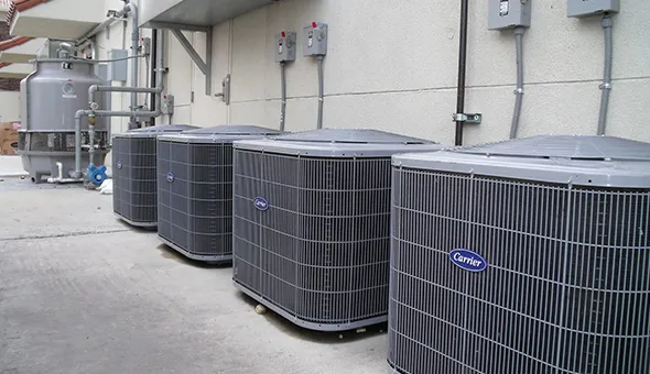 Row of several outdoor HVAC units installed on a commercial building, showcasing efficient cooling solutions.