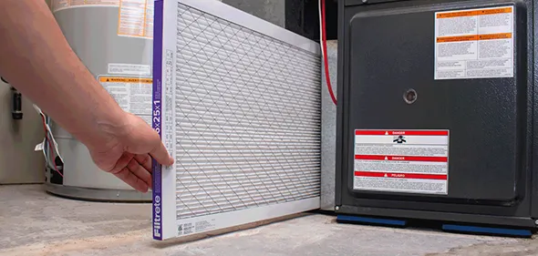 Technician changing a furnace filter in Sparks, NV, demonstrating essential maintenance for optimal heating system performance.